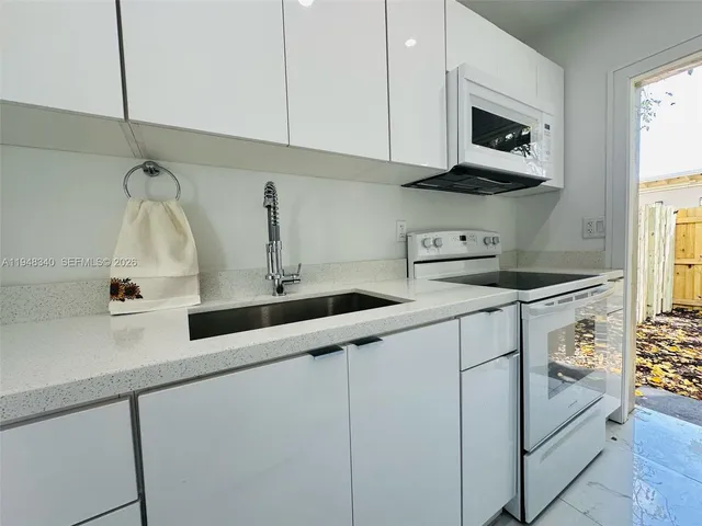 a kitchen with stainless steel appliances granite countertop white cabinets and a sink