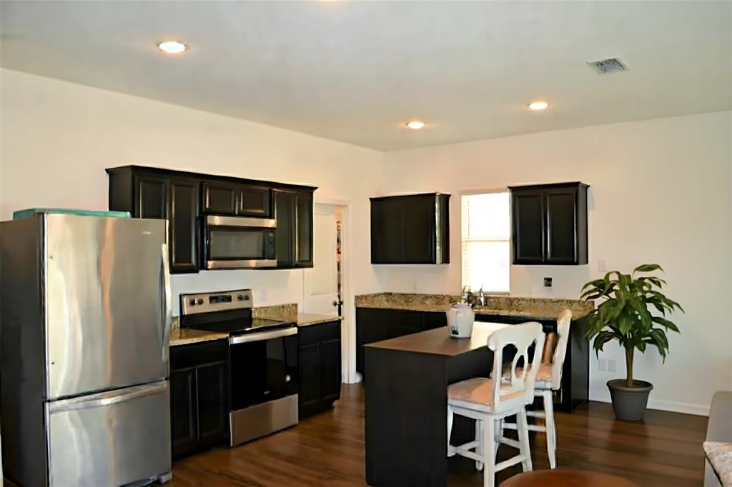 801 Peach Tree Lane Anna, TX 75409 - Photo 5 of 14 a kitchen with stainless steel appliances a microwave a stove a refrigerator a stove a microwave a dining table and chairs with wooden floor