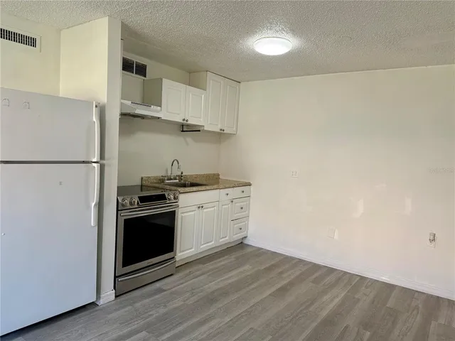 a kitchen with stainless steel appliances white cabinets and wooden floor