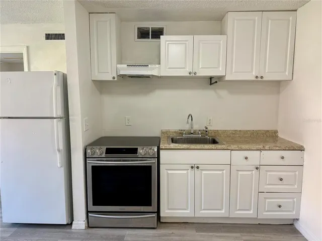 a kitchen with granite countertop white cabinets and refrigerator