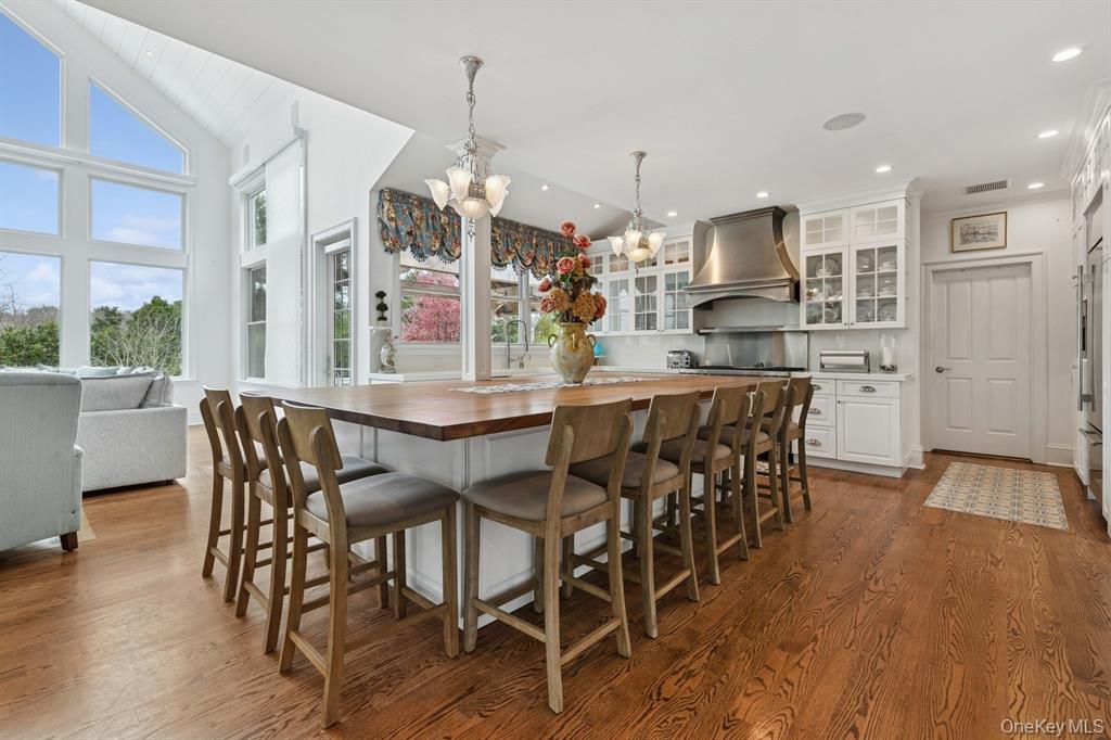 15 Carter Road Hampton Bays, NY 11946 - Photo 13 of 47 Kitchen with butcher block counters, a kitchen breakfast bar, glass insert cabinets, white cabinets, and pendant lighting