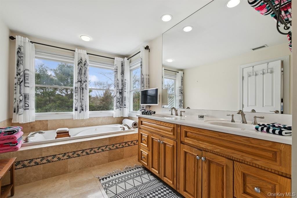 15 Carter Road Hampton Bays, NY 11946 - Photo 31 of 47 Bathroom with double vanity, a garden tub, recessed lighting, and light tile patterned floors