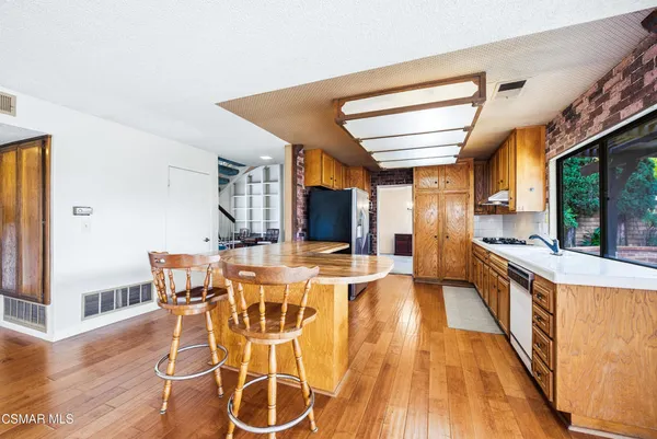 a kitchen with stainless steel appliances granite countertop a refrigerator a stove and a sink with wooden floor