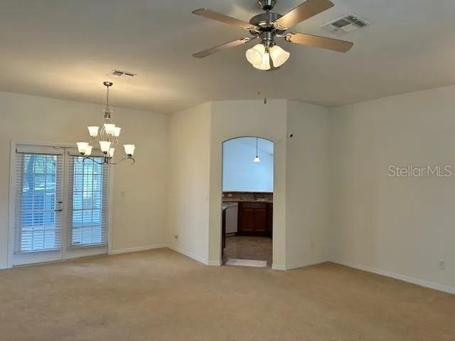 a view of an empty room with a chandelier fan