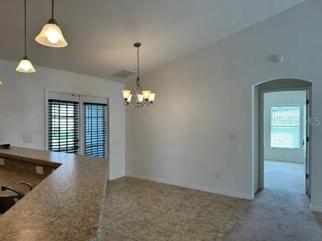 a view of a livingroom with a chandelier fan and windows