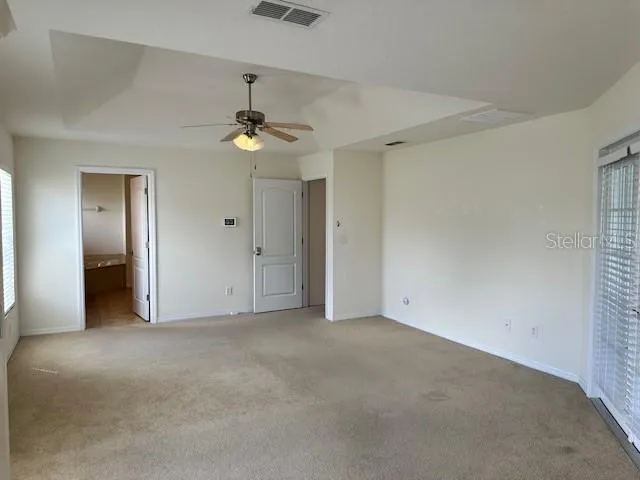 an empty room with windows and chandelier fan