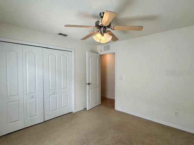 an empty room with a window and a fan
