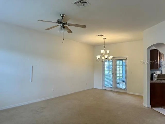 an empty room with chandelier fan and windows