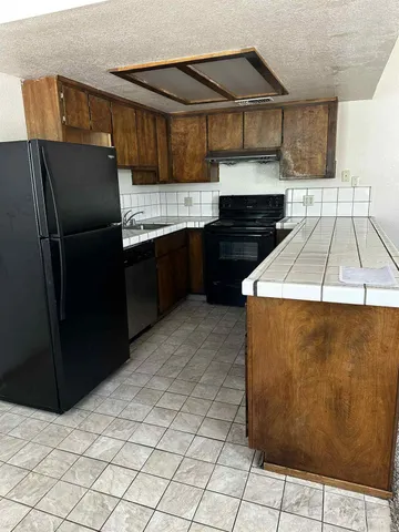 a kitchen with granite countertop a refrigerator and a stove top oven