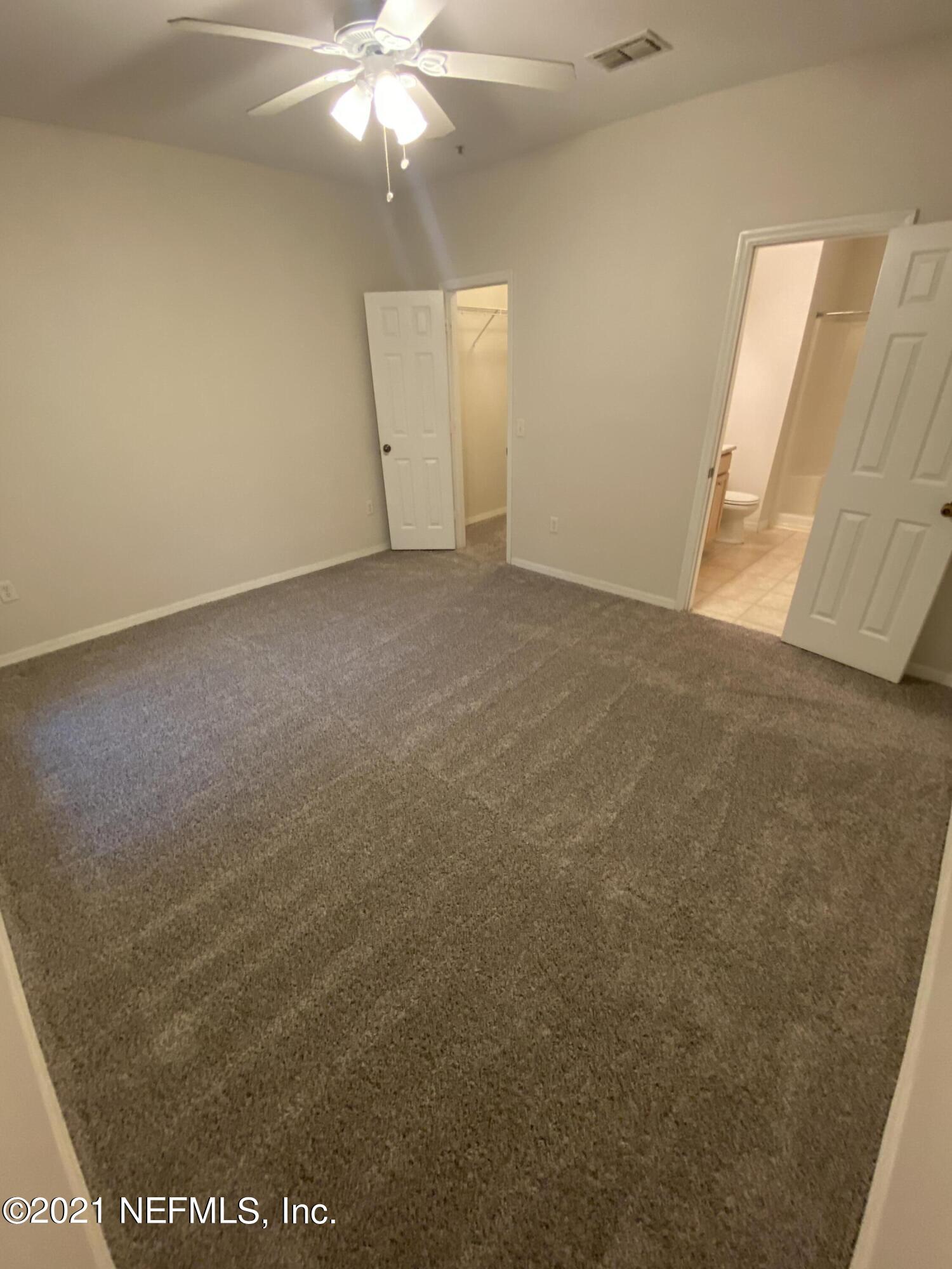 7800 Point Meadows Drive, Unit 422 Jacksonville, FL 32256 - Photo 12 of 38 an empty room with a chandelier fan and windows