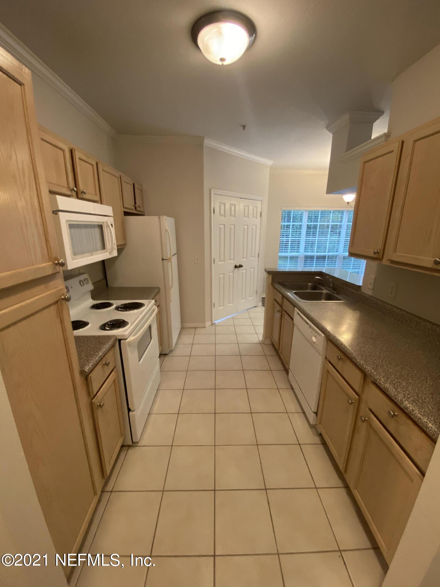 7800 Point Meadows Drive, Unit 422 Jacksonville, FL 32256 - Photo 29 of 38 a kitchen with granite countertop a sink a stove a refrigerator and cabinets