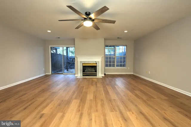 a view of an empty room with wooden floor and a fireplace