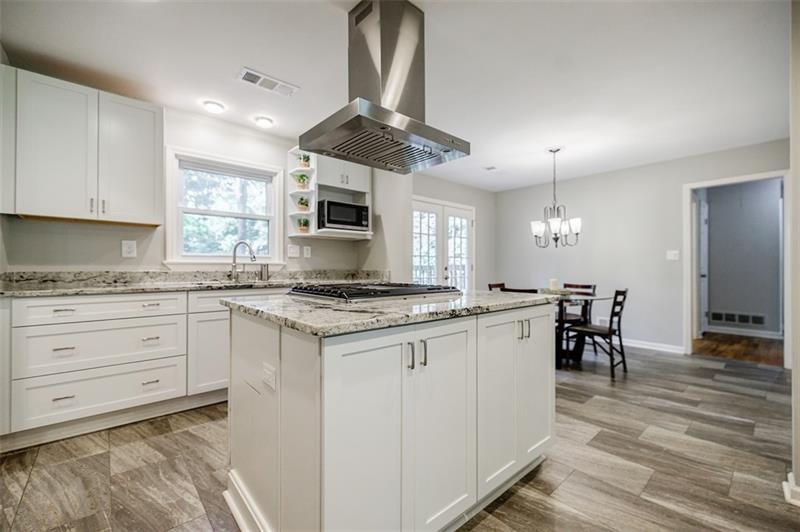 2343 Hunting Valley Drive Decatur, GA 30033 - Photo 16 of 71 a kitchen with kitchen island granite countertop a stove a sink a dining table and chairs with wooden floor