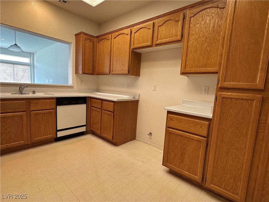 3213 Partridge Run Street Laughlin, NV 89029 - Photo 23 of 37 Kitchen featuring light floors, dishwasher, light countertops, brown cabinetry, and a sink