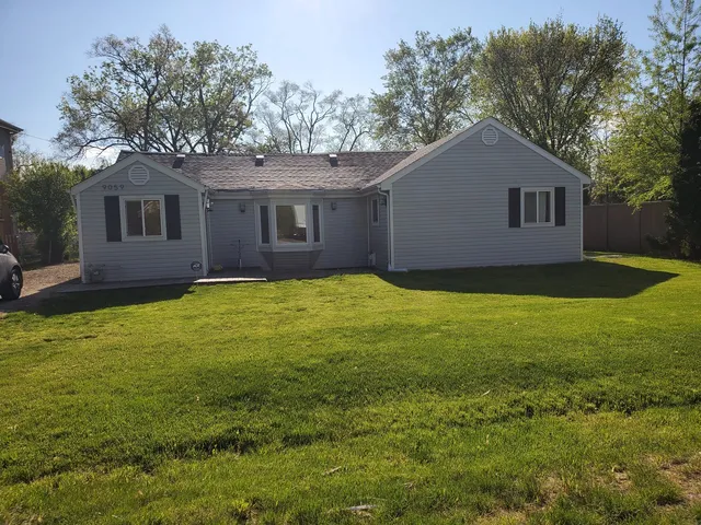 a house that is sitting in the grass with tress in the background