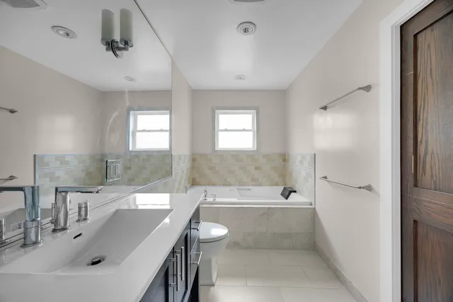 a bathroom with a bathtub shower sink and mirror