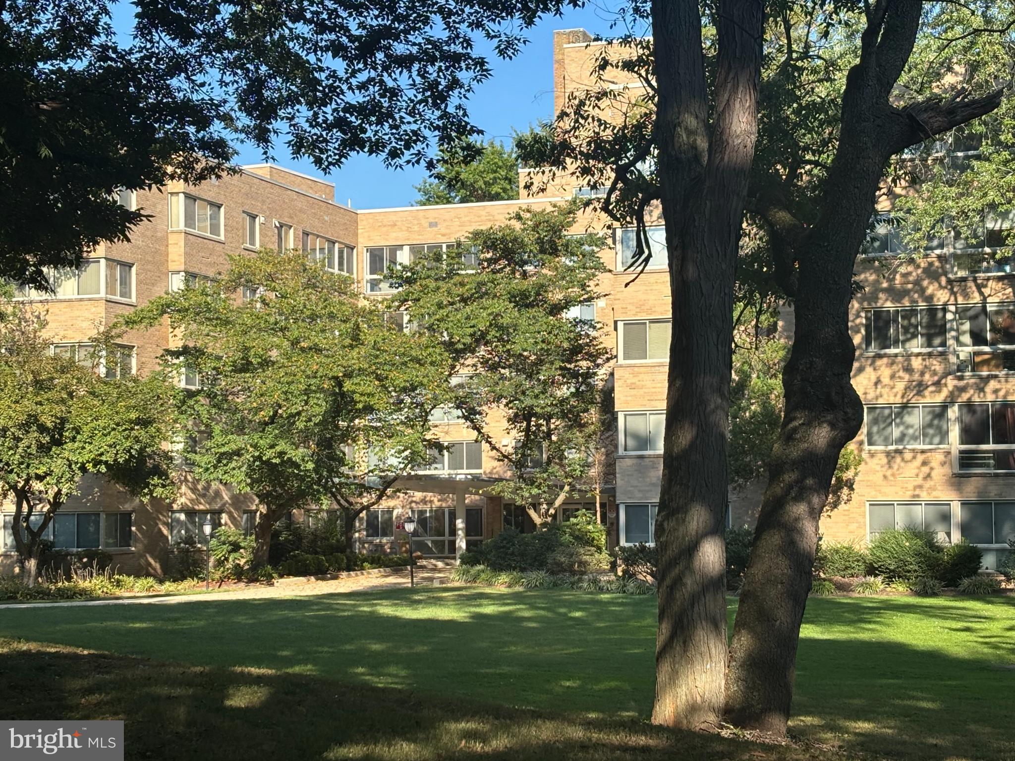 a view of a white house next to a yard with big trees
