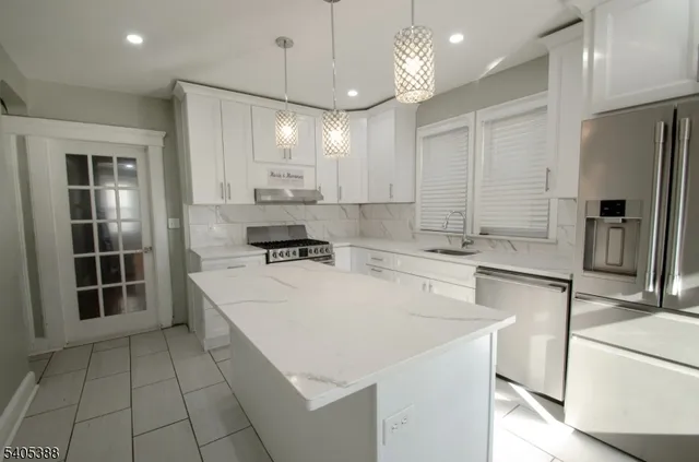 a large kitchen with stainless steel appliances a refrigerator a sink dishwasher a stove and a dining table with wooden floor