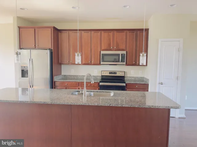 a kitchen with stainless steel appliances granite countertop a refrigerator microwave and sink