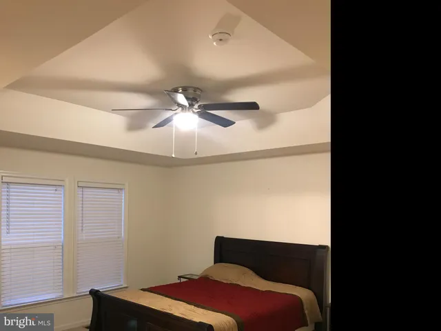 a bedroom with a bed and a chandelier fan