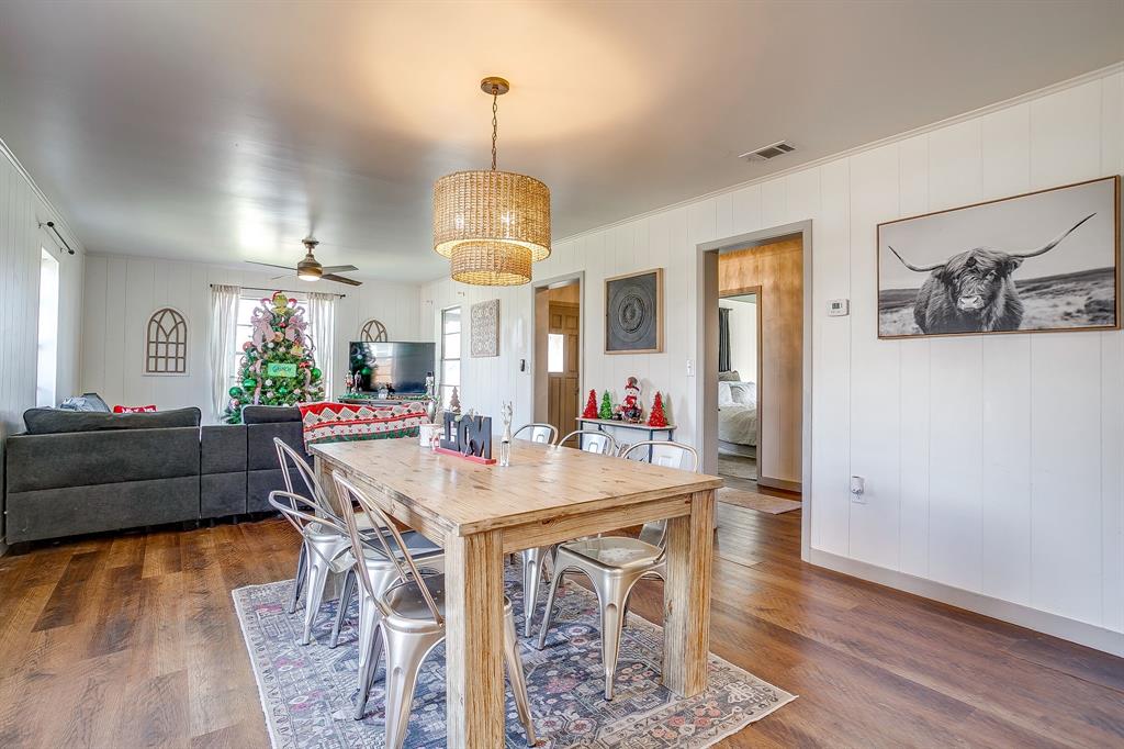 610 North Mesquite Hico, TX 76457 - Photo 11 of 34 Dining room with a ceiling fan, dark wood-style floors, and wood walls