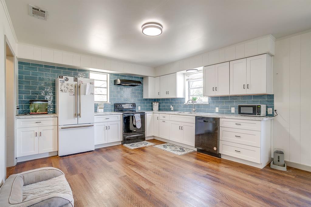 610 North Mesquite Hico, TX 76457 - Photo 14 of 34 Kitchen with black appliances, white cabinetry, backsplash, and light wood-type flooring