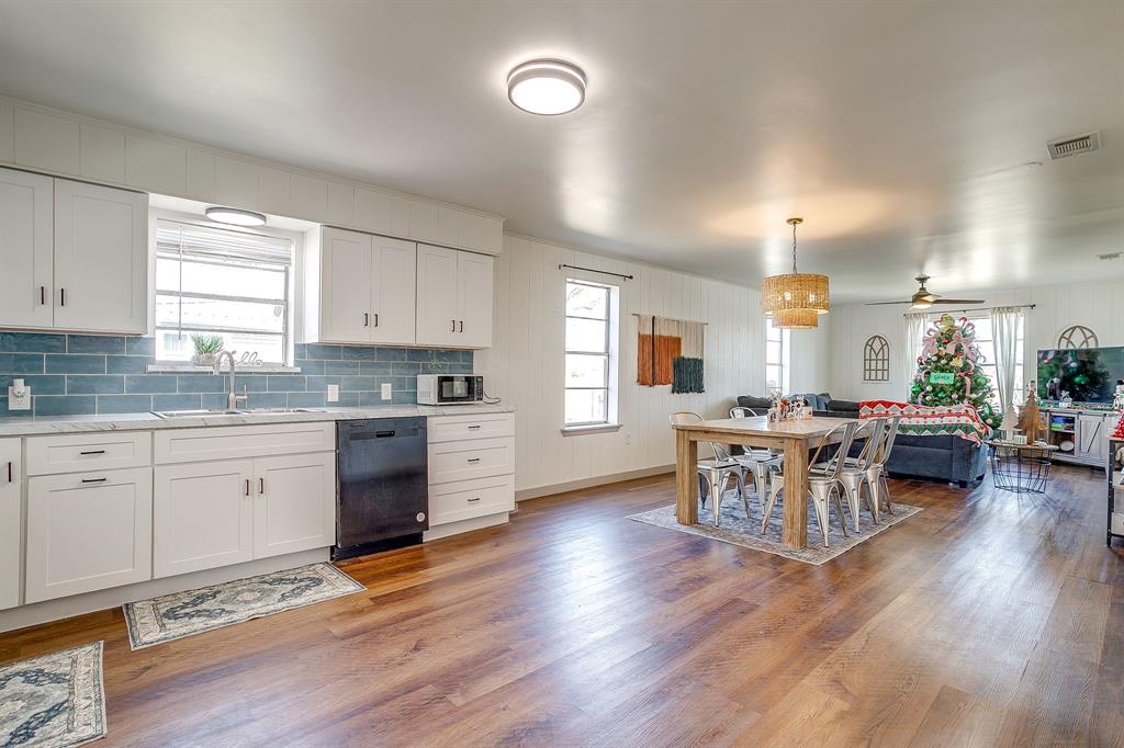 610 North Mesquite Hico, TX 76457 - Photo 18 of 34 Kitchen featuring white cabinets, healthy amount of natural light, tasteful backsplash, dishwasher, and wooden walls