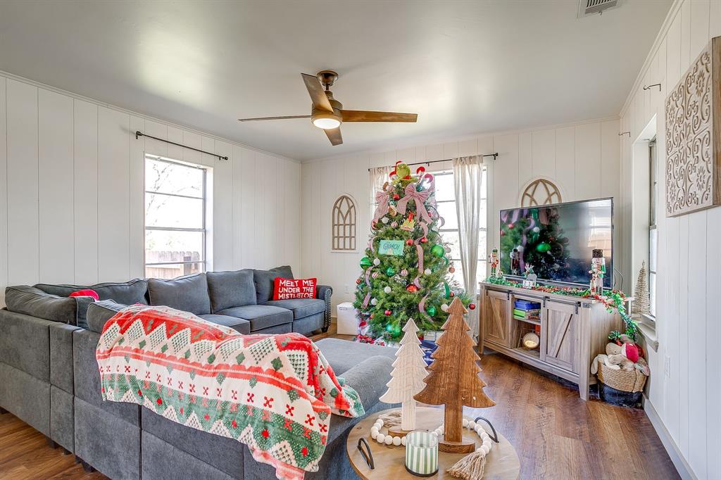 610 North Mesquite Hico, TX 76457 - Photo 5 of 34 Living area featuring wood finished floors, ceiling fan, wood walls, healthy amount of natural light, and ornamental molding