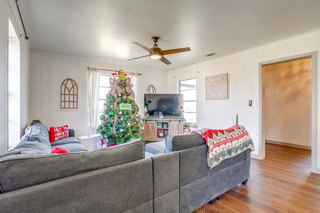 610 North Mesquite Hico, TX 76457 - Photo 7 of 34 Living area featuring wood finished floors, a ceiling fan, plenty of natural light, and wood walls