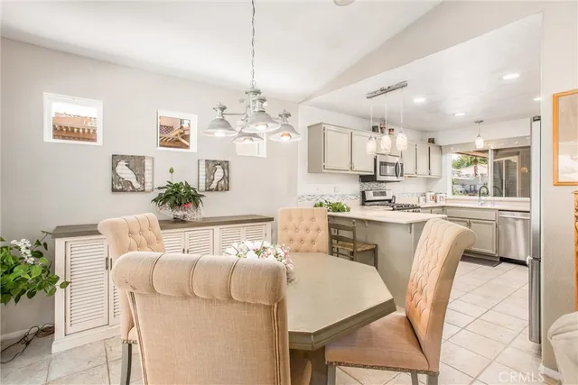 a dining room with kitchen island stainless steel appliances furniture a chandelier and kitchen view