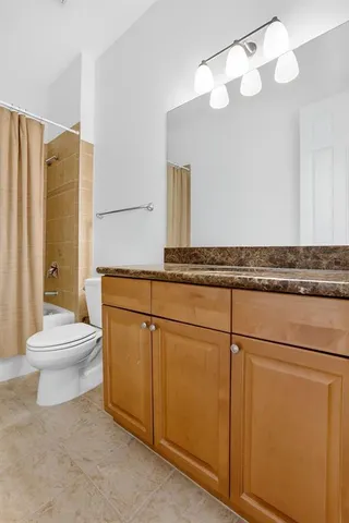 a bathroom with a granite countertop sink a toilet and a mirror