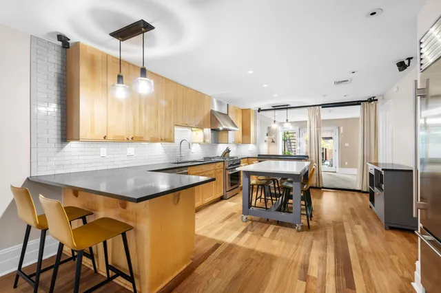 a kitchen with a table chairs refrigerator and wooden floor