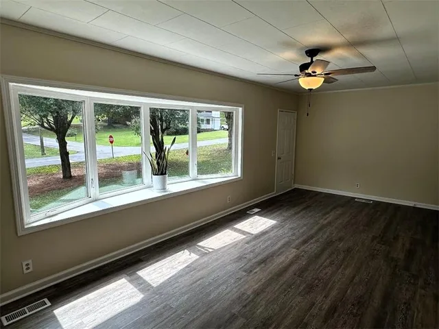a view of an empty room with wooden floor and a window