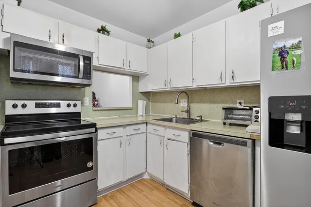 a kitchen with cabinets stainless steel appliances and wooden floor