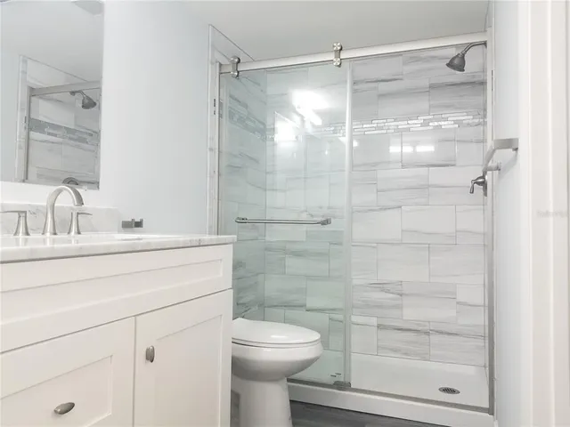 a bathroom with a granite countertop bathtub shower sink vanity and toilet