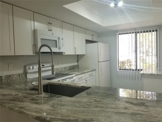 a kitchen with stainless steel appliances granite countertop a sink a stove and a refrigerator