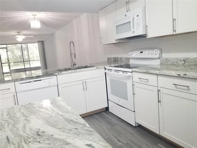 a kitchen with white cabinets appliances and a sink