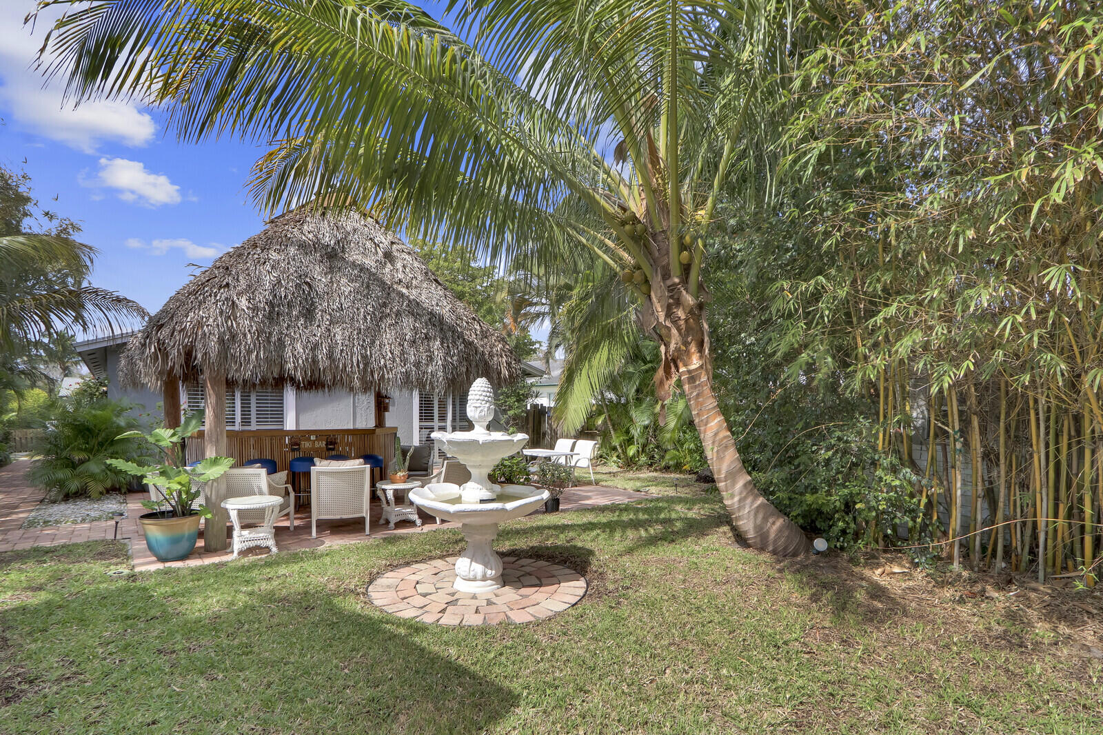 503 North Perry Avenue Jupiter, FL 33458 - Photo 14 of 44 a white house with a large tree and lawn chairs under an umbrella