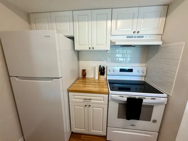 a kitchen with stainless steel appliances white cabinets and a refrigerator