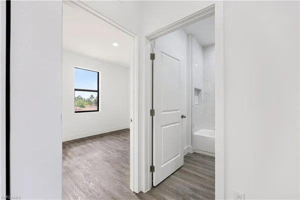 a view of a hallway with wooden floor and a bathroom