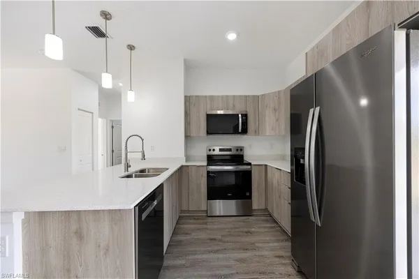 a kitchen with stainless steel appliances granite countertop a refrigerator a sink a stove top oven and wooden floor