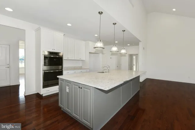 a kitchen with kitchen island granite countertop a sink a counter top space and living room view