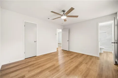 a view of an empty room with wooden floor and a ceiling fan