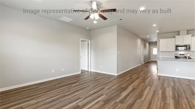 a view of an empty room with window and wooden floor