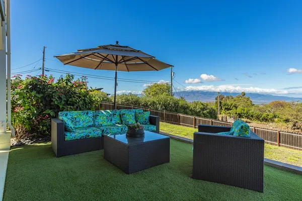 a view of a backyard with couches plants and an umbrella