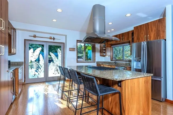 a kitchen with stainless steel appliances granite countertop a stove a refrigerator a sink a dining table and chairs with wooden floor