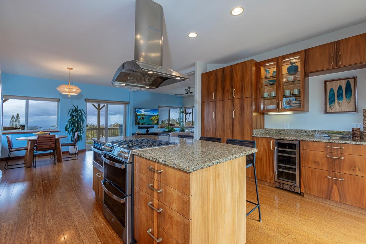 1350 Naalae Road Kula, HI 96790 - Photo 49 of 50 a kitchen with stainless steel appliances granite countertop a stove oven a dining table and chairs with wooden floor