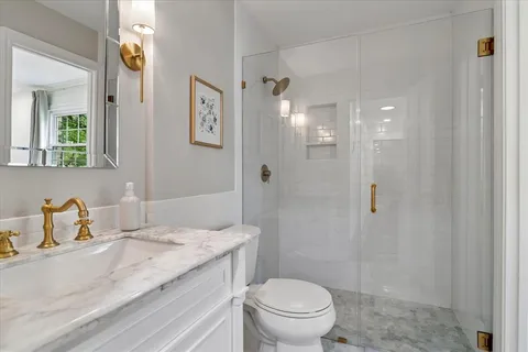a bathroom with a granite countertop sink a toilet and shower
