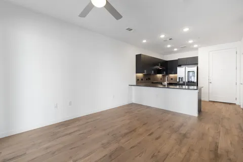 an empty room with wooden floor chandelier fan and windows