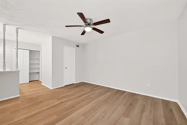 a view of empty room with wooden floor and ceiling fan